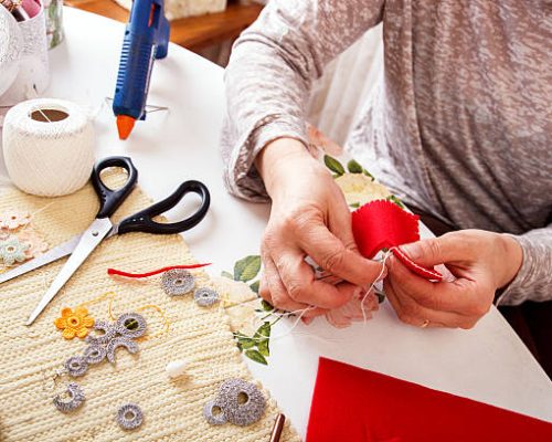 Senior women sews by hand and making heart shape ornament.